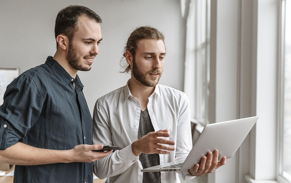 Dvaja IT software testeri držiac laptop v stoji diskutujú o nástrojoch pre automatizované testovanie softvéru