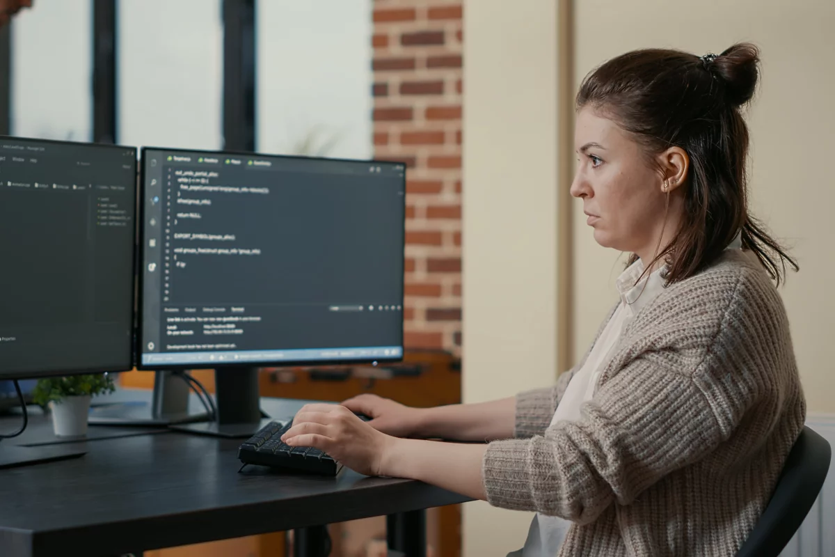 Testerka automatizovaného testovania píše kód na klávesnici a pozrá do monitora