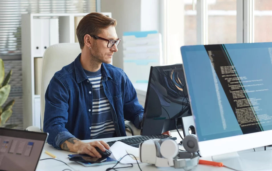A young male it tester looks into a monitor and works on a computer
