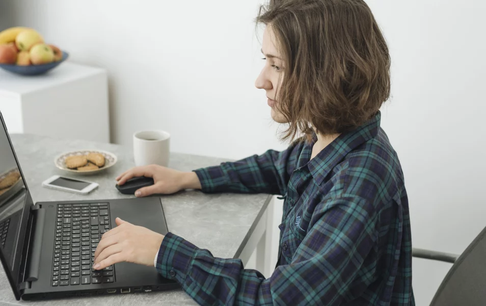 mladá žena bruneta v kockovanej košeli pracuje na laptope